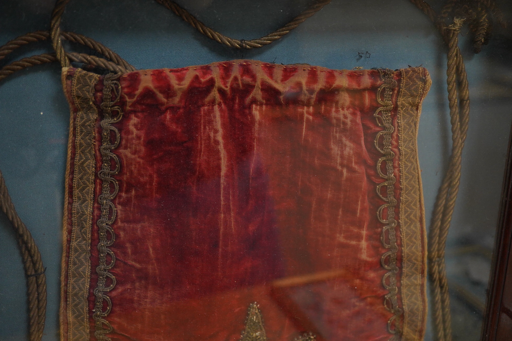 Eton interest - a commemorative William IV, ceremonial red velvet, gold metallic thread, tasselled and braided bag, mounted within a mahogany glazed cabinet. An old printed ticket in Latin mounted beneath: Pro More et Mo